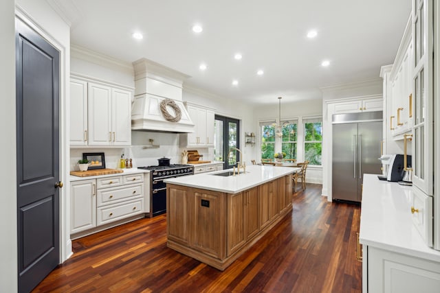 kitchen featuring a kitchen island with sink, sink, white cabinets, and premium appliances