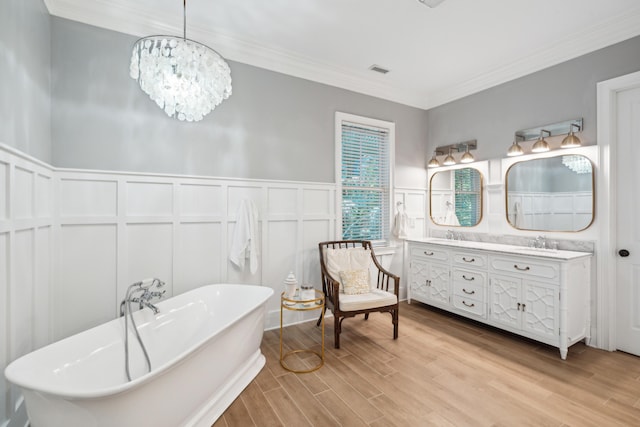 bathroom featuring crown molding, hardwood / wood-style floors, vanity, a notable chandelier, and a tub to relax in