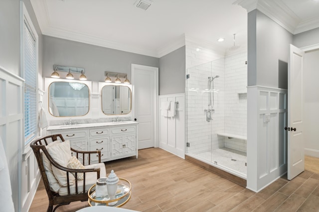 bathroom with a shower with door, vanity, and ornamental molding