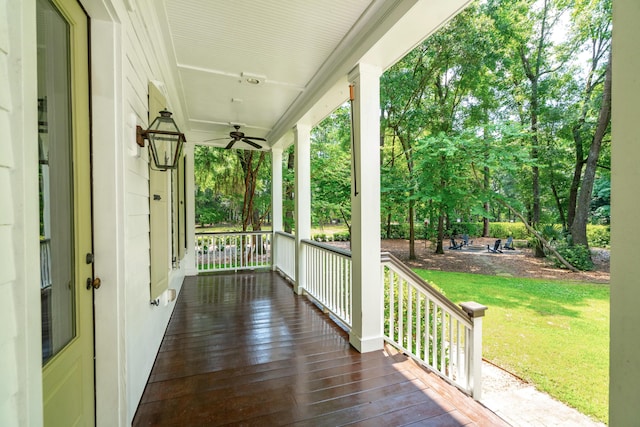 wooden terrace with ceiling fan, covered porch, and a lawn