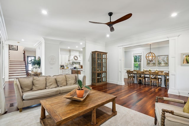 living room featuring ceiling fan with notable chandelier, wood-type flooring, and ornamental molding