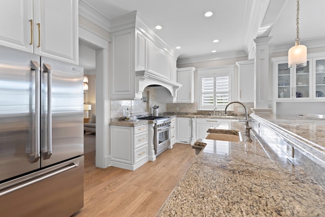 kitchen featuring backsplash, ornamental molding, white cabinetry, high quality appliances, and light wood-type flooring