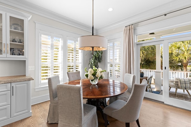 dining room featuring light wood-style flooring, ornamental molding, baseboards, and french doors