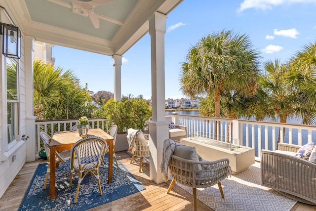 deck with a water view, ceiling fan, and outdoor lounge area