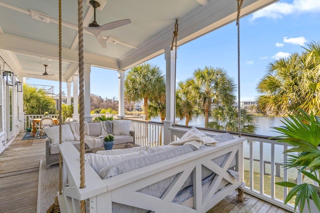 wooden terrace featuring a ceiling fan, a water view, and outdoor lounge area