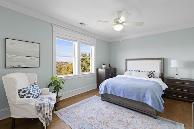 bedroom featuring visible vents, crown molding, baseboards, and wood finished floors