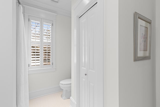 bathroom with a closet, toilet, and baseboards