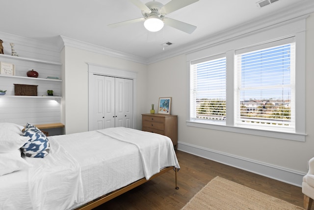 bedroom with baseboards, ceiling fan, ornamental molding, wood finished floors, and a closet