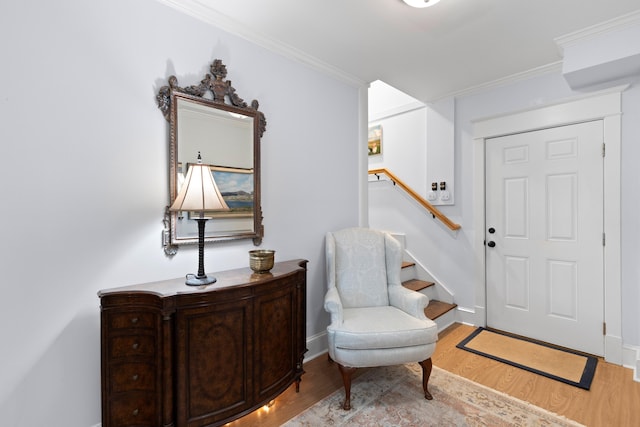 entryway with stairway, light wood-style flooring, ornamental molding, and baseboards