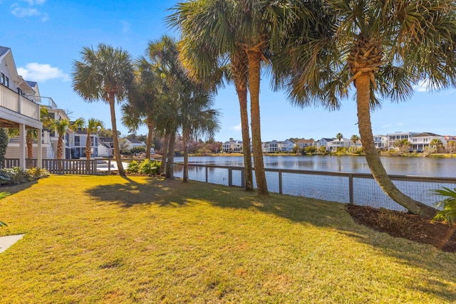 view of yard featuring a residential view, a water view, and fence