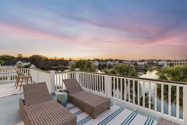 deck at dusk featuring a water view and a residential view