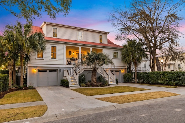 beach home with stucco siding, a porch, stairway, a garage, and driveway