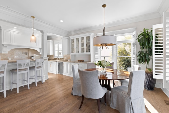 dining room featuring light wood-type flooring, decorative columns, crown molding, and recessed lighting