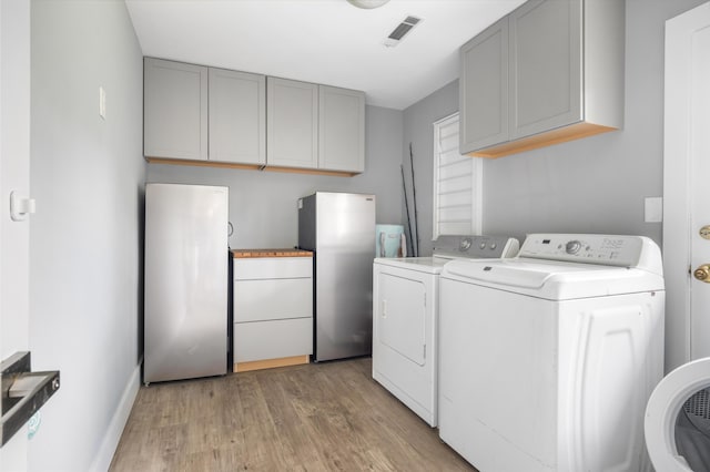 laundry room featuring washing machine and dryer, light wood-type flooring, and baseboards