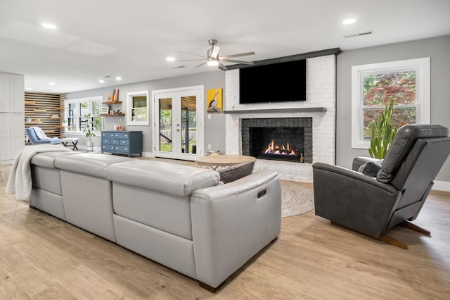 living room with ceiling fan, recessed lighting, light wood-style flooring, a brick fireplace, and plenty of natural light