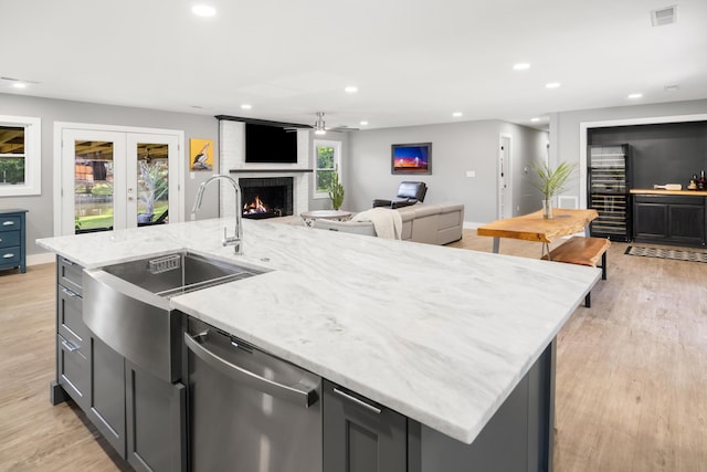 kitchen with dishwasher, open floor plan, a sink, a center island with sink, and recessed lighting