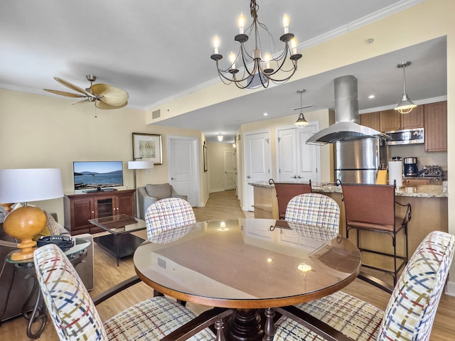 dining space with visible vents, crown molding, light wood finished floors, and ceiling fan with notable chandelier