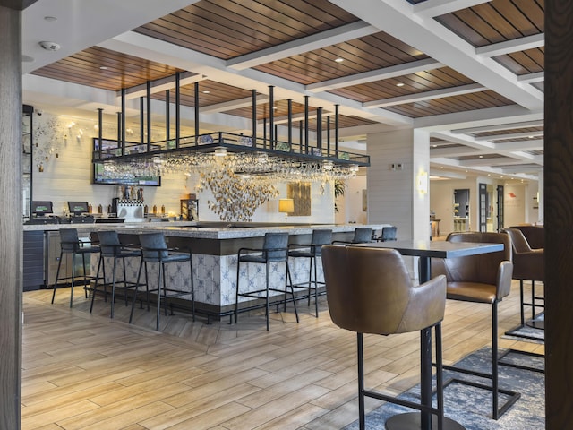 bar with beamed ceiling, wood finished floors, and a community bar