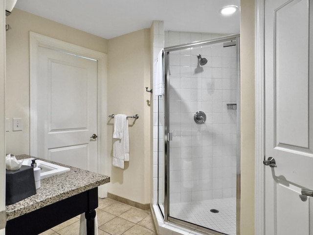 full bathroom with a stall shower, vanity, baseboards, and tile patterned floors