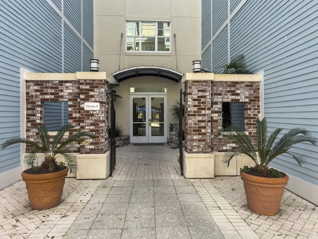 property entrance featuring french doors, brick siding, and stucco siding