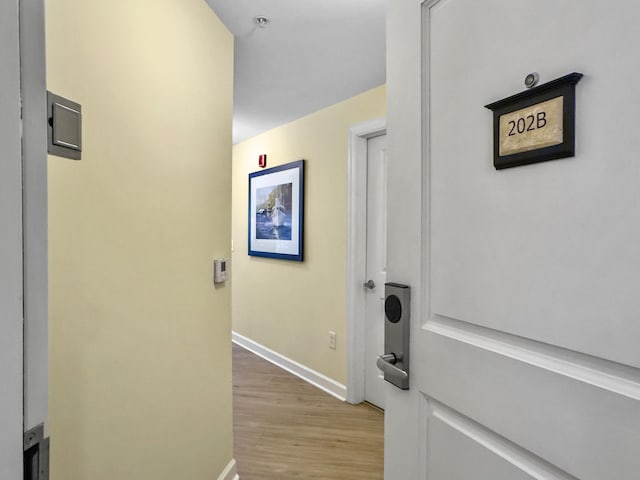 hallway with light wood-type flooring and baseboards