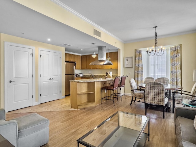 living area featuring visible vents, baseboards, light wood-style floors, ornamental molding, and an inviting chandelier