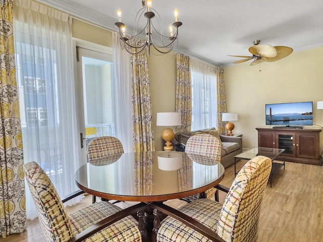 dining space with ceiling fan with notable chandelier, crown molding, and wood finished floors