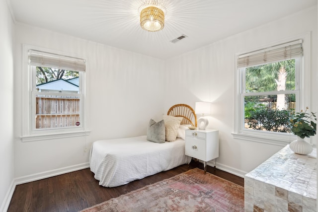 bedroom with multiple windows and dark wood-type flooring