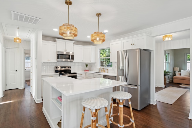 kitchen with sink, white cabinetry, a center island, appliances with stainless steel finishes, and pendant lighting