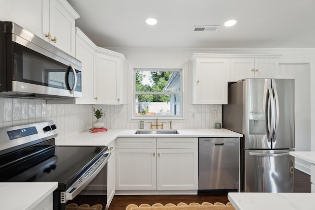 kitchen featuring tasteful backsplash, sink, white cabinets, and appliances with stainless steel finishes