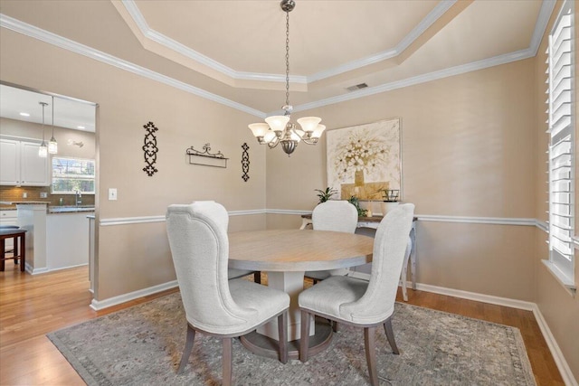 dining area featuring visible vents, baseboards, light wood-style floors, a raised ceiling, and a chandelier