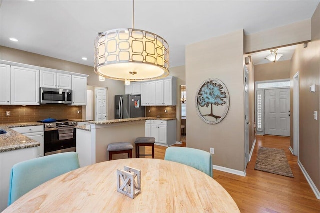 dining space with recessed lighting, light wood-style flooring, and baseboards