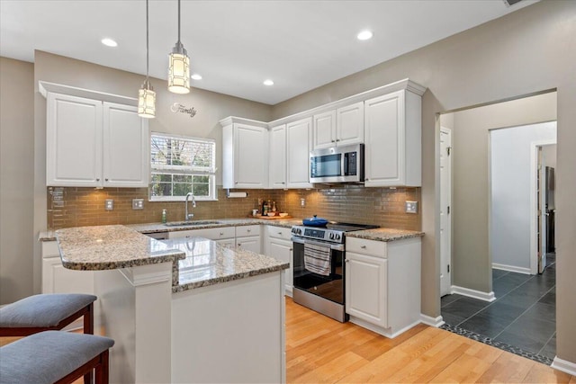 kitchen with white cabinets, stainless steel appliances, light wood-type flooring, and a sink