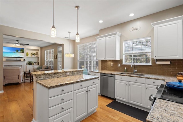 kitchen with light wood-style flooring, dishwasher, a kitchen island, and a sink