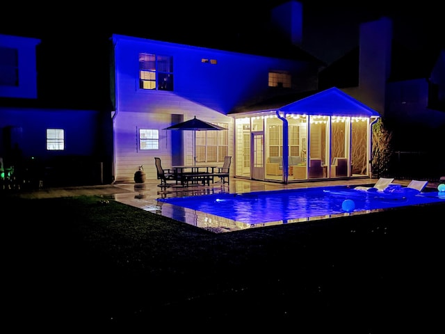 pool at night with a patio and an outdoor pool