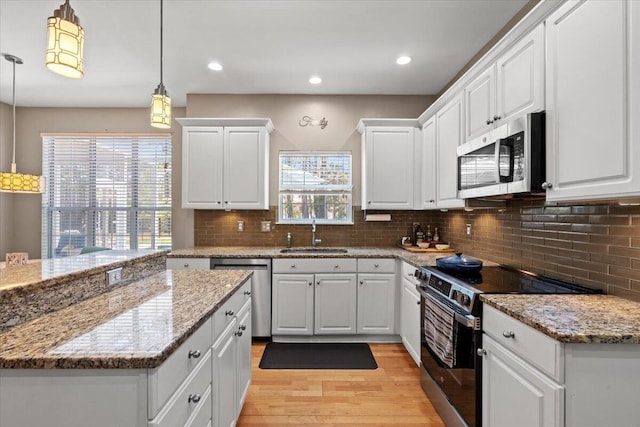 kitchen with backsplash, appliances with stainless steel finishes, light wood-style floors, white cabinets, and a sink