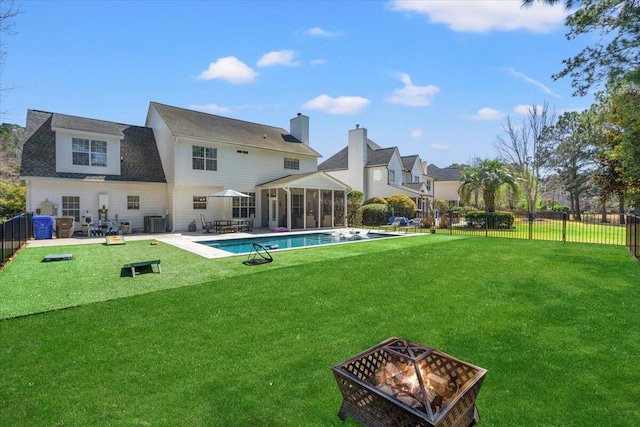 rear view of property with fence, a patio area, a lawn, and a fire pit