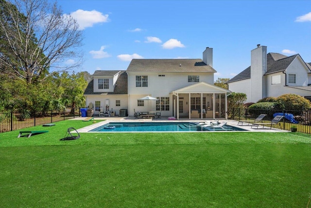 rear view of house featuring a patio, a lawn, fence, and a sunroom