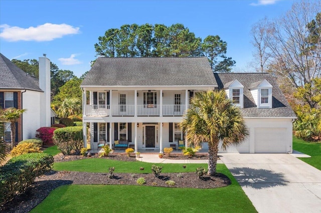 colonial inspired home with a shingled roof, a front lawn, a porch, concrete driveway, and a garage