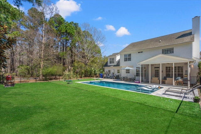 view of swimming pool with a yard, a sunroom, a patio, and fence