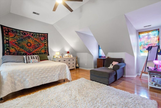 bedroom with vaulted ceiling, visible vents, baseboards, and wood finished floors