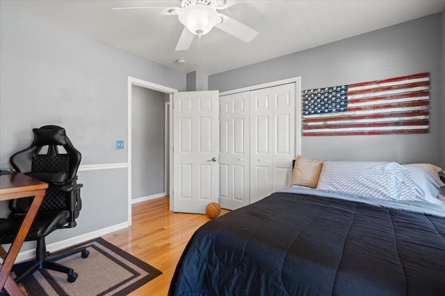 bedroom featuring a closet, baseboards, wood finished floors, and a ceiling fan