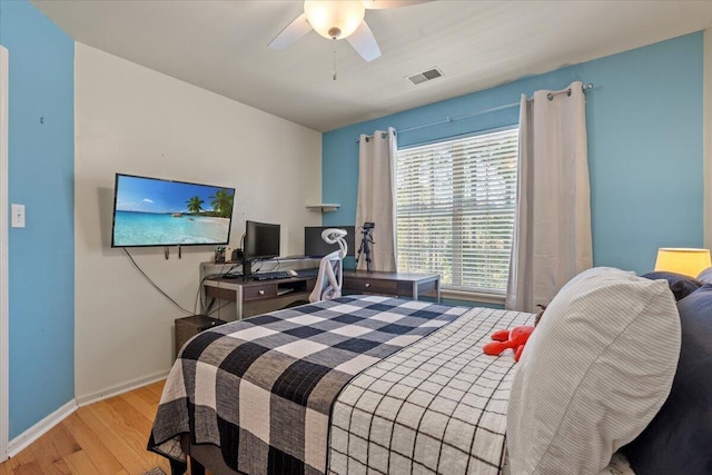 bedroom with ceiling fan, visible vents, baseboards, and wood finished floors