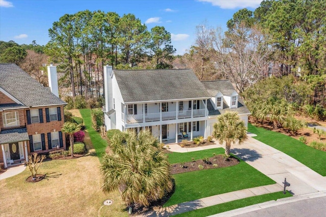 view of front of property featuring a front lawn, a balcony, a porch, and driveway