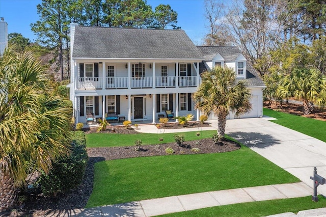 view of front of home with a garage, covered porch, driveway, and a front lawn