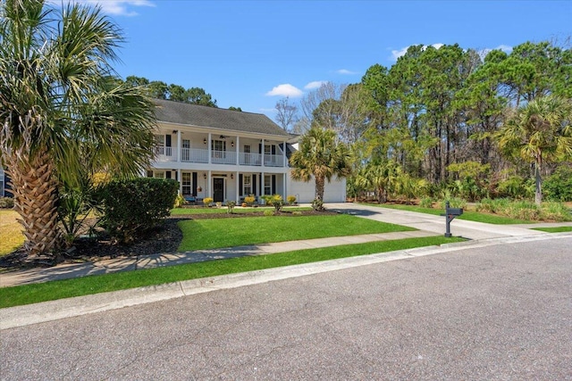 colonial home with a balcony, an attached garage, covered porch, concrete driveway, and a front lawn