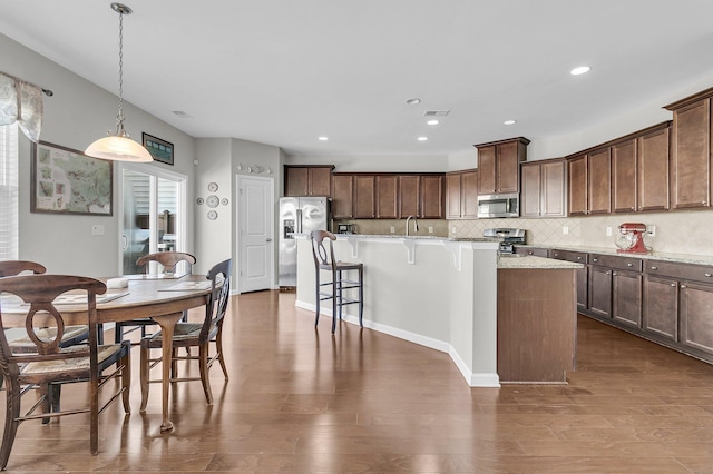 kitchen with appliances with stainless steel finishes, tasteful backsplash, a wealth of natural light, decorative light fixtures, and a center island