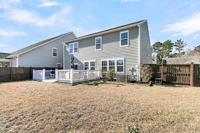 back of house featuring a lawn and a wooden deck