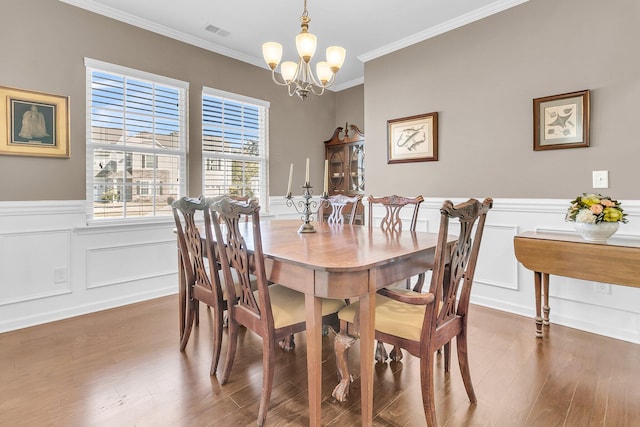 dining area featuring hardwood / wood-style flooring, a notable chandelier, and ornamental molding