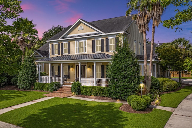 view of front facade featuring a front yard, a standing seam roof, covered porch, and metal roof